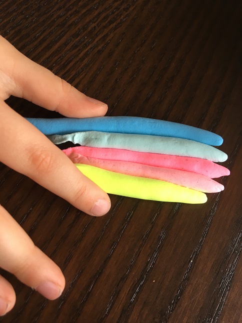 Bunte Knetwürstchen liegen nebeneinander wie ein Regenbogen