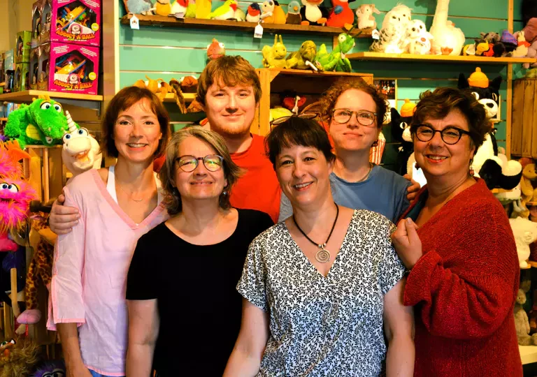 Das Team von Salima Kinderschätze: sechs Menschen im Laden vor den Regalen mit Kuscheltieren