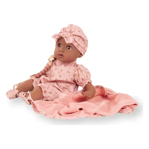 Babypuppe Cosy Aquini von Götz mit dunkler Haut und rosa Kleidung auf einer Decke