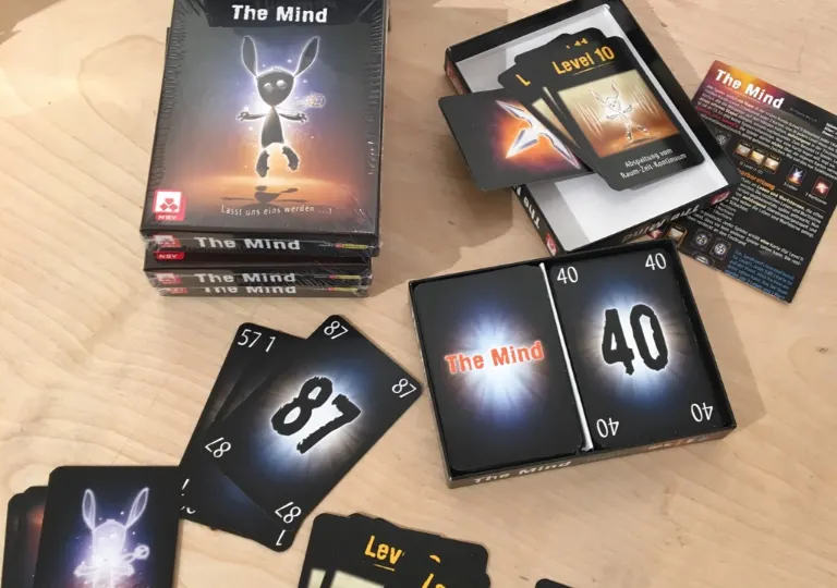 Ausgepacktes Kartenspiel The Mind mit Spielkarten auf einem Holztisch