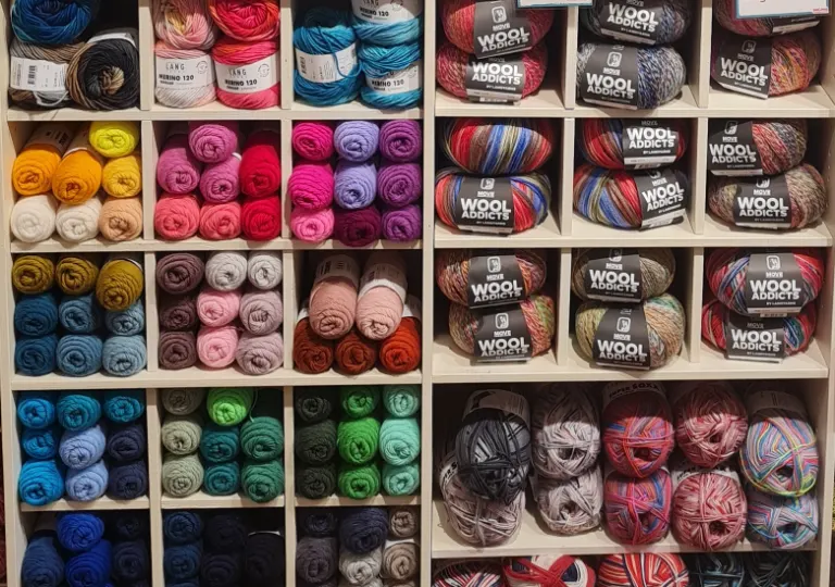 Regalwand bei Salima mit bunten Wollknäueln von Lang Yarns und Wool Addicts, nach Farben sortiert